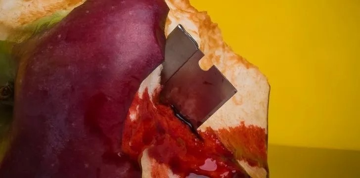 O lamă de ras ascuțită în interiorul unui măr pe jumătate mâncat și plin de sânge.
